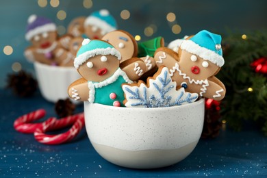 Photo of Delicious homemade Christmas cookies in bowl on blue wooden table against blurred festive lights