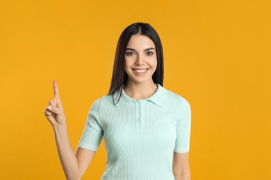 Woman showing number one with her hand on yellow background