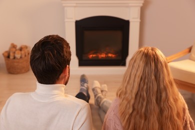 Lovely couple spending time together near fireplace at home, back view