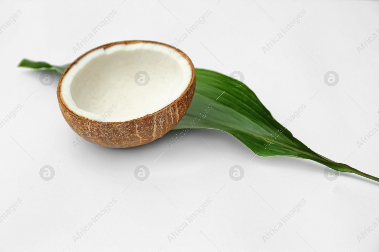 Photo of Half of fresh coconut and palm leaf on white background