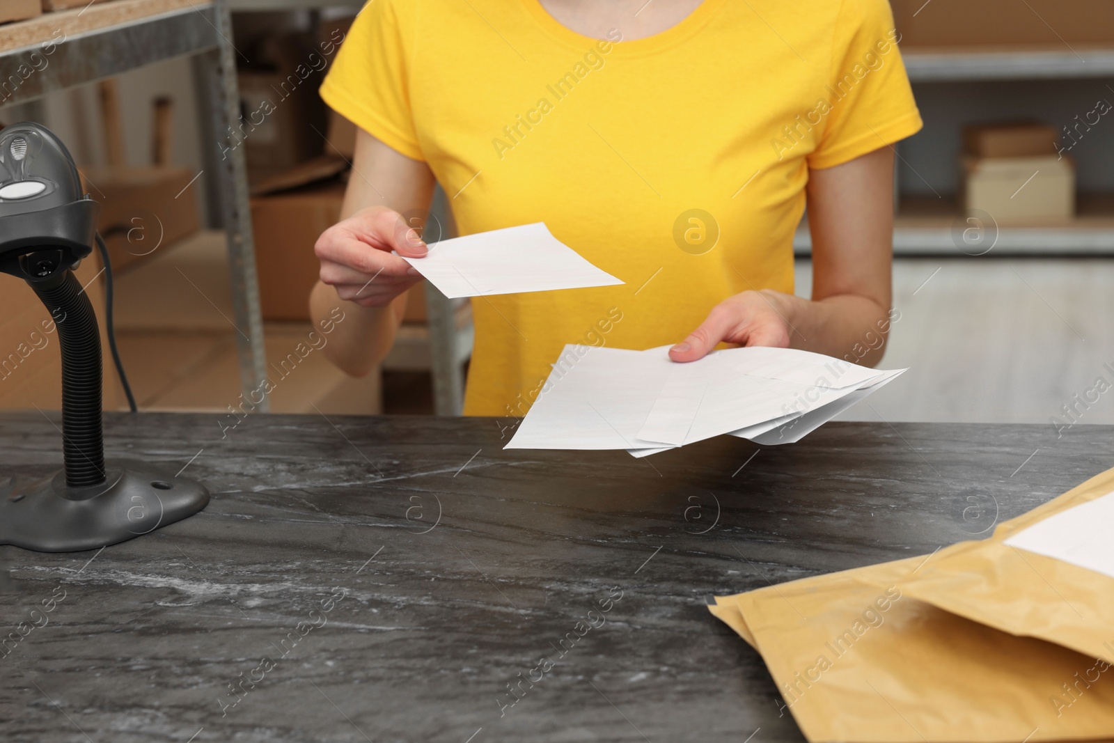 Photo of Post office worker with envelopes at counter indoors, closeup