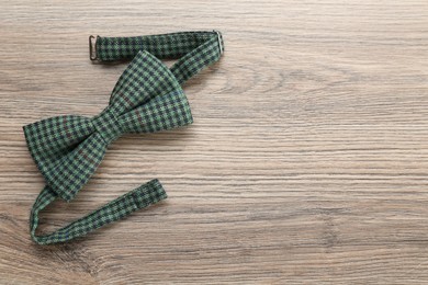 Stylish gingham bow tie on wooden background, top view. Space for text