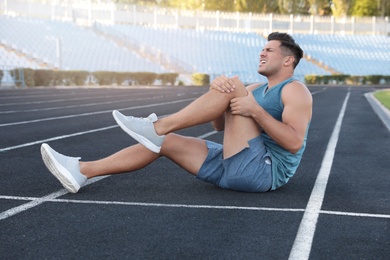 Photo of Man in sportswear having knee problems at stadium