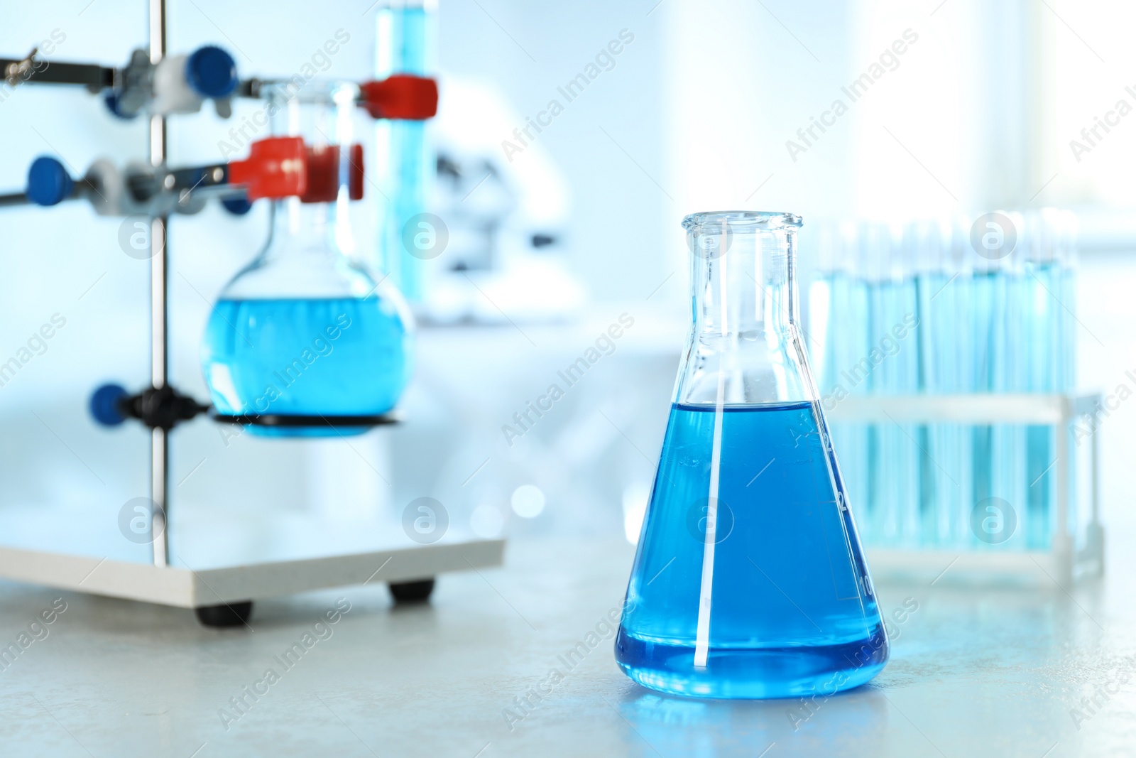 Photo of Conical flask with light blue liquid on table in laboratory. Space for text