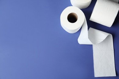 Toilet paper rolls and space for text on color background, top view