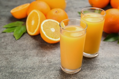 Photo of Delicious orange juice and fresh fruits on grey table. Space for text