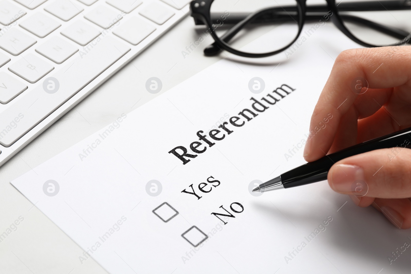 Photo of Woman with referendum ballot making decision at white table, closeup