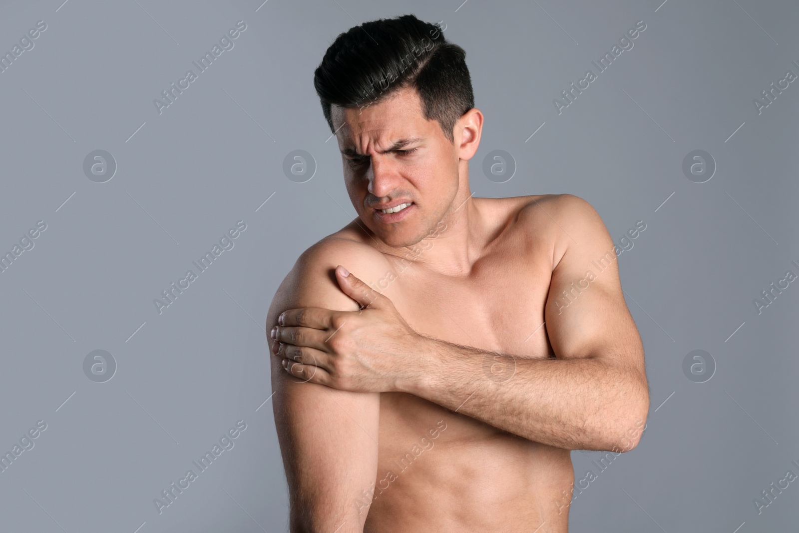 Photo of Man suffering from shoulder pain on grey background