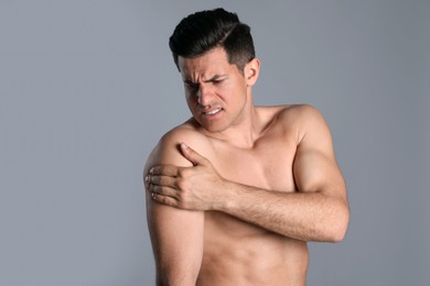 Man suffering from shoulder pain on grey background