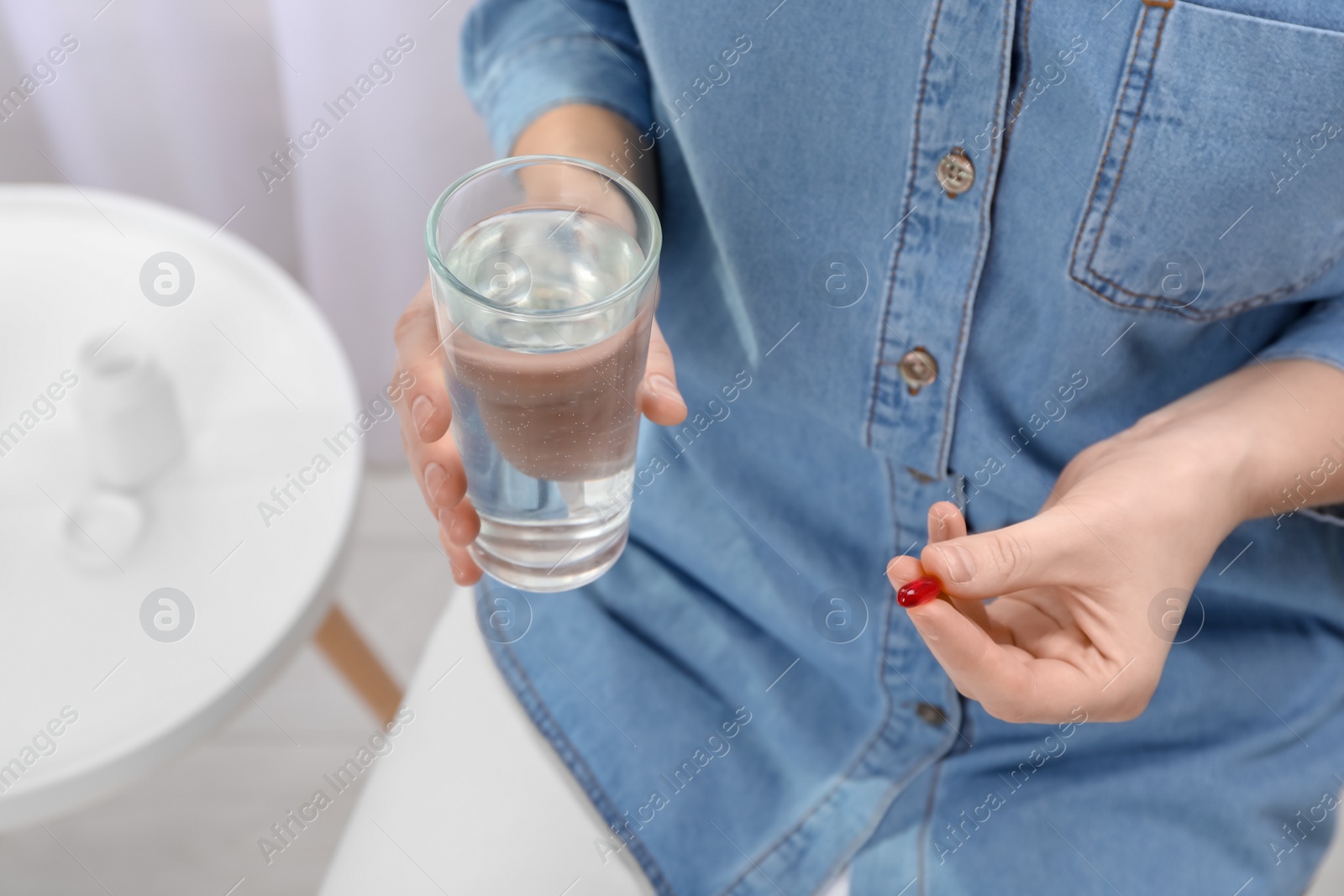 Photo of Young woman with pill and glass of water, closeup