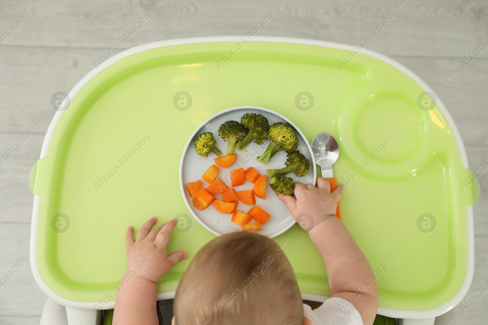 Photo of Cute little baby eating healthy food, top view