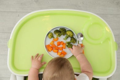 Cute little baby eating healthy food, top view