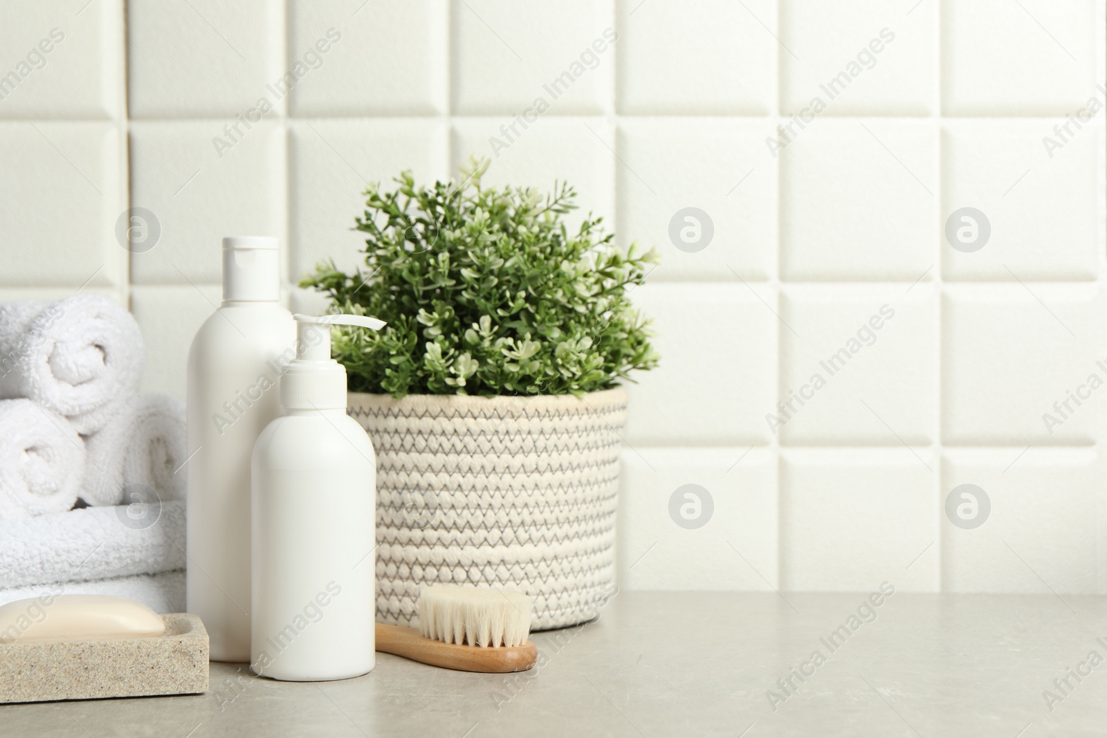 Photo of Different bath accessories and personal care products on gray table near white tiled wall, space for text