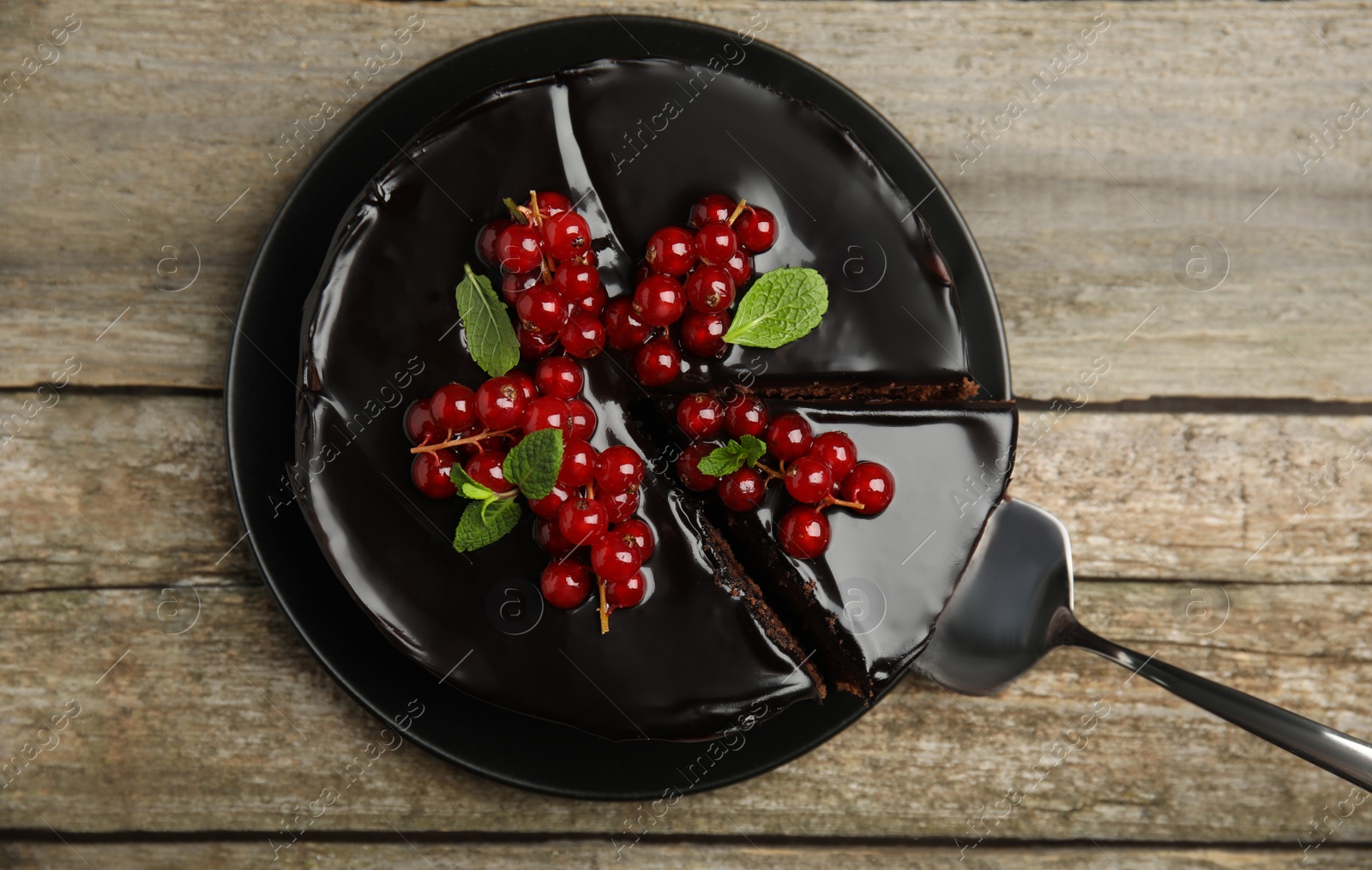 Photo of Tasty homemade chocolate cake with berries and mint on wooden table, top view