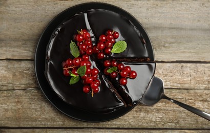 Photo of Tasty homemade chocolate cake with berries and mint on wooden table, top view