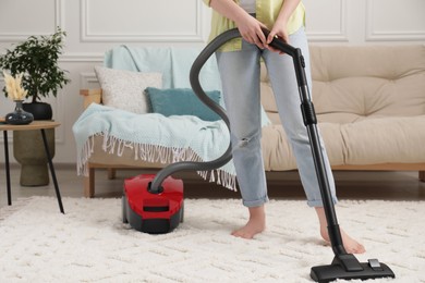 Photo of Woman cleaning carpet with vacuum cleaner at home, closeup. Space for text