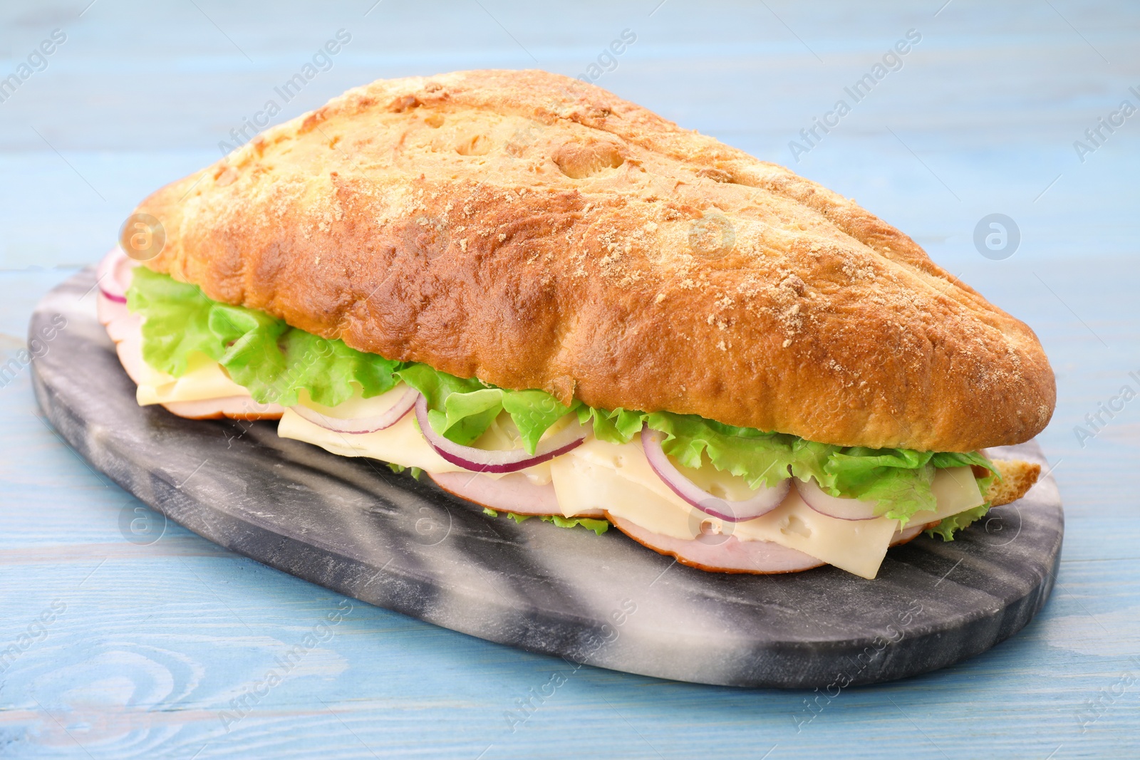 Photo of Delicious sandwich with fresh vegetables and cheese on light blue wooden table, closeup