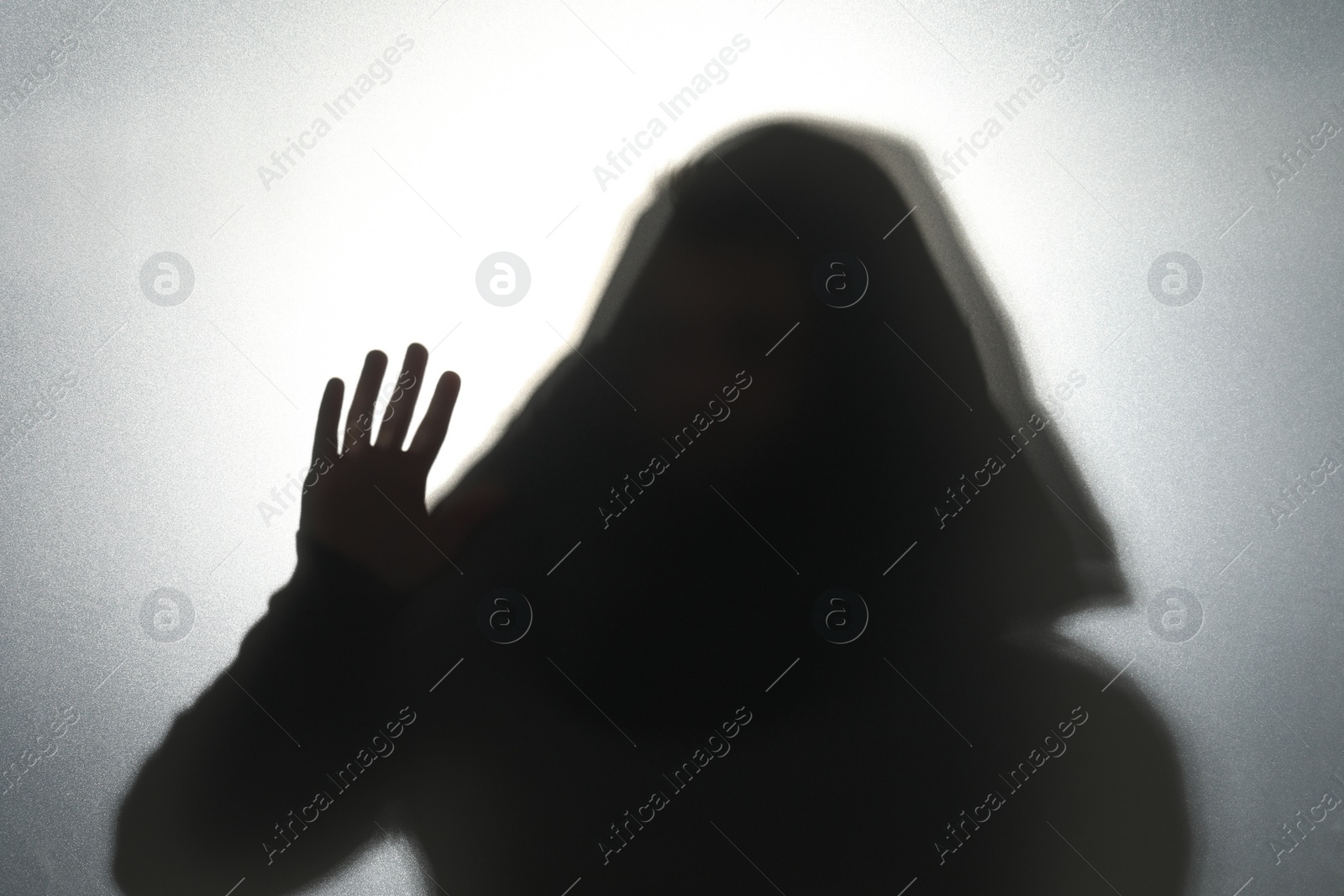 Photo of Silhouette of ghost behind glass against grey background