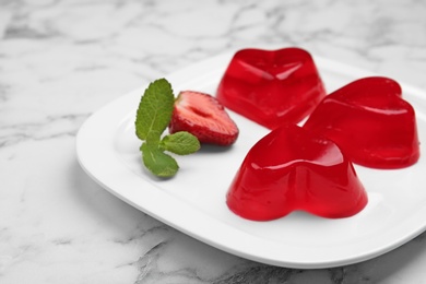 Photo of Plate of tasty strawberry jelly on marble table, space for text