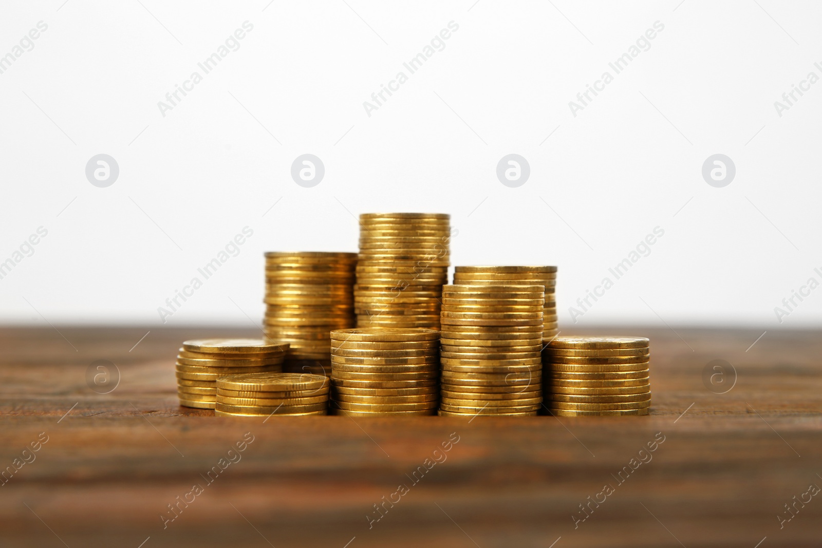 Photo of Many stacks of coins on table against light background