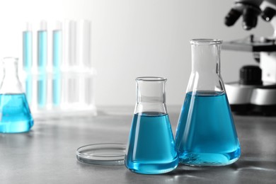 Photo of Different laboratory glassware with light blue liquid on table. Space for text