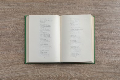 Photo of Open hardcover book on wooden table, top view