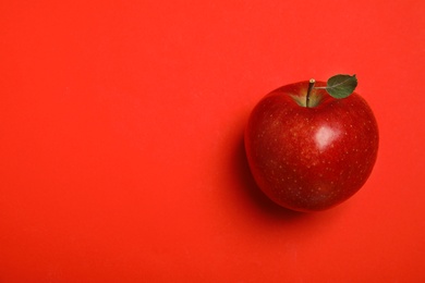 Photo of Ripe juicy apple with leaf on red background, top view. Space for text