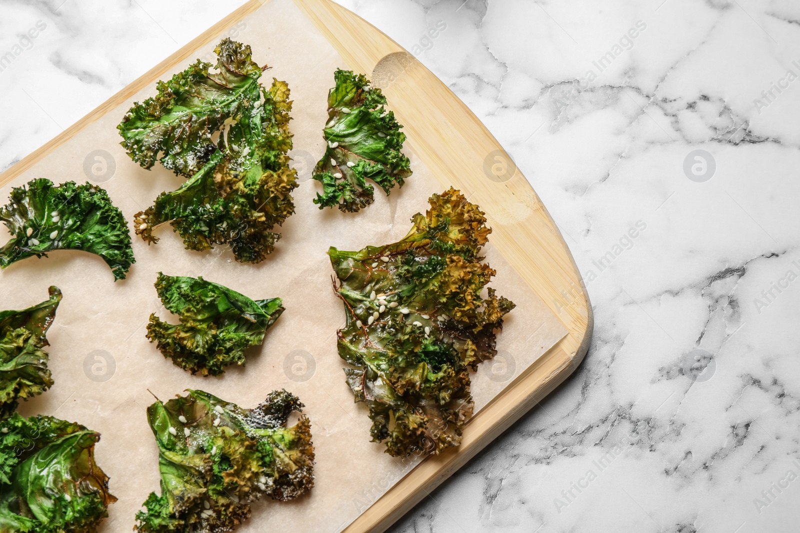 Photo of Tasty baked kale chips on marble table, top view