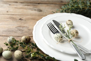 Festive Easter table setting with quail eggs and floral decor on wooden background, closeup