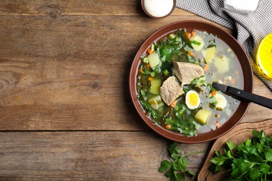 Photo of Delicious sorrel soup with meat and egg served on wooden table, flat lay. Space for text