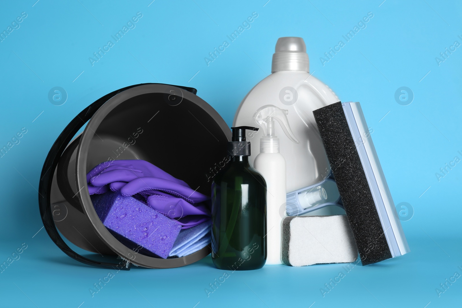 Photo of Black bucket, cleaning supplies and tools on light blue background