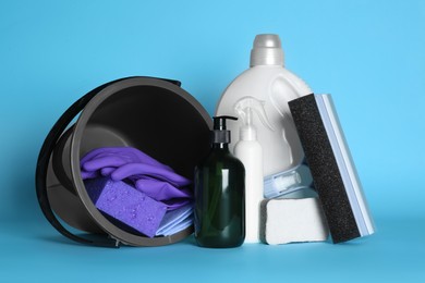 Photo of Black bucket, cleaning supplies and tools on light blue background