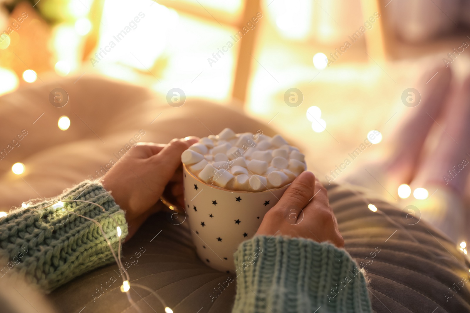 Photo of Woman holding cup of hot drink with marshmallows indoors, closeup. Magic Christmas atmosphere