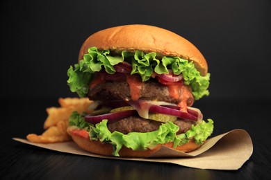 Tasty burger with vegetables, patties and lettuce served on wooden table, closeup