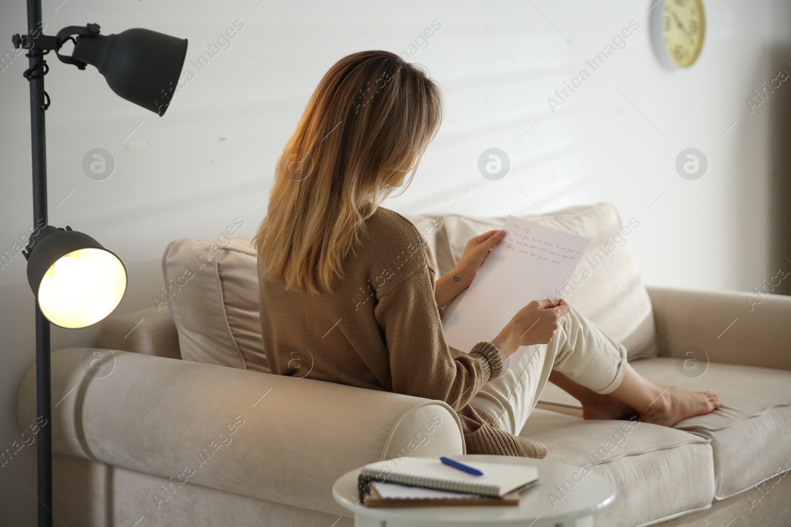 Photo of Woman reading letter on sofa at home