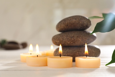 Photo of Composition with spa stones and candles on white wooden table