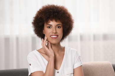 Portrait of beautiful young woman near window indoors