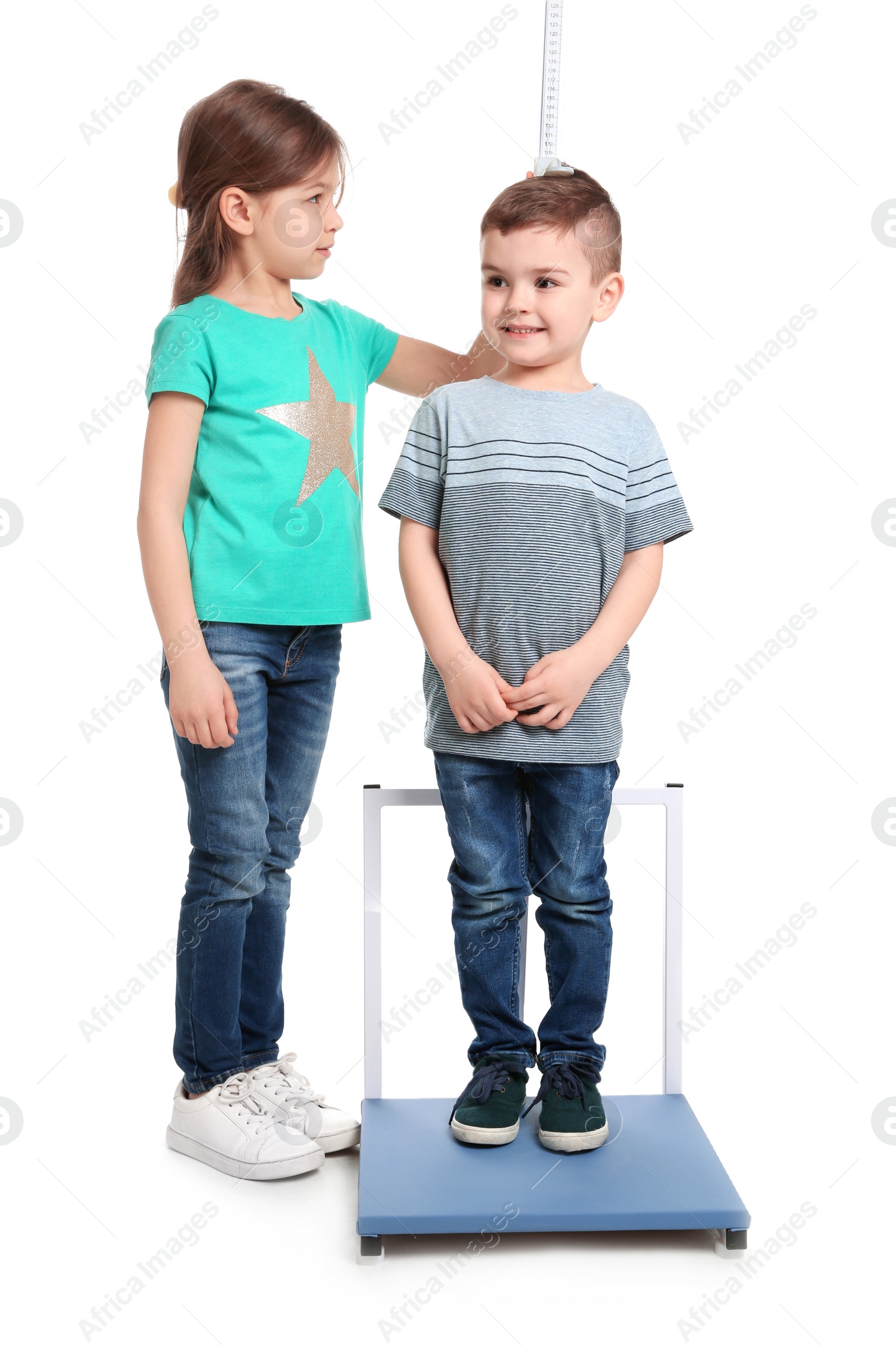 Photo of Little girl measuring boy's height on white background