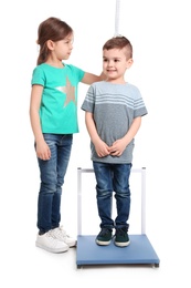 Little girl measuring boy's height on white background