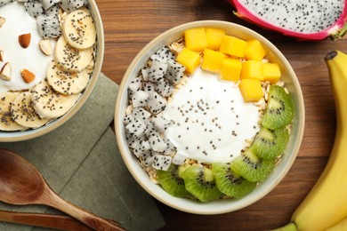 Photo of Bowls of granola with yogurt and fruits on wooden table, flat lay