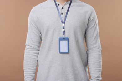 Man with blank badge on beige background, closeup