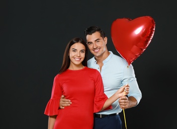 Photo of Beautiful couple with heart shaped balloon on dark background