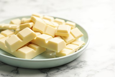 Photo of Delicious white chocolate pieces on marble table, closeup