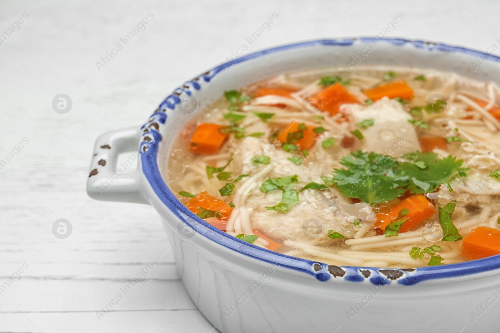 Photo of Dish with fresh homemade chicken soup on wooden table, closeup. Space for text