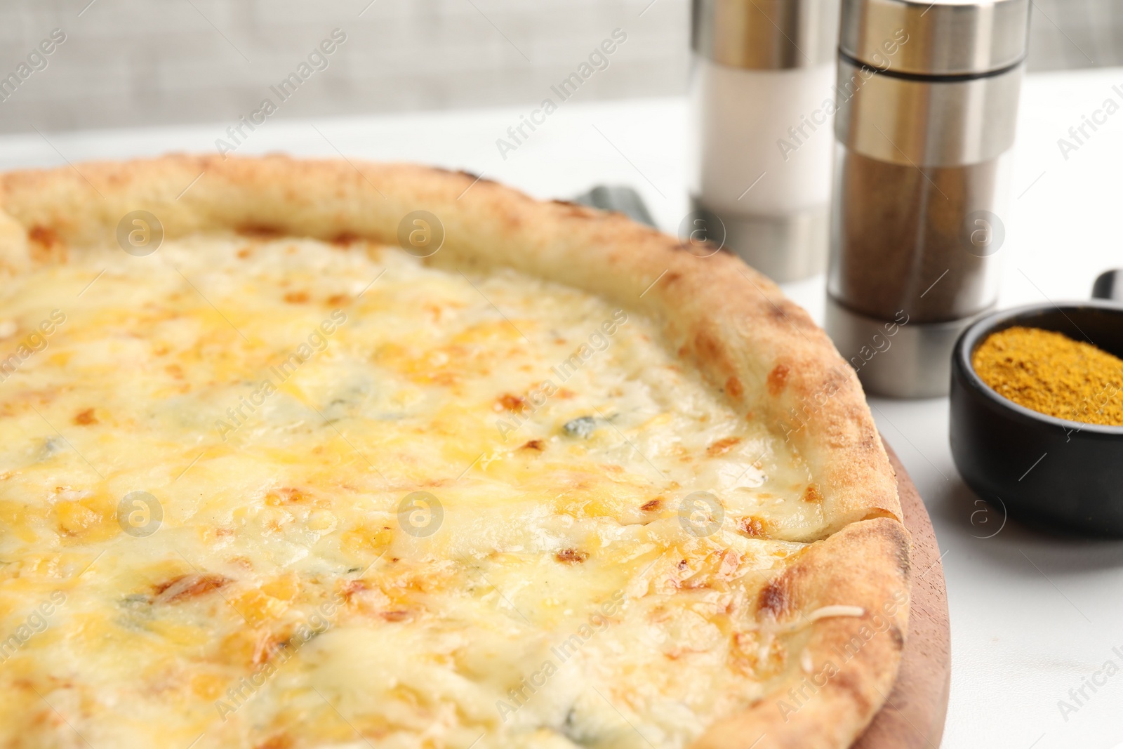 Photo of Delicious cheese pizza and spices on white table, closeup