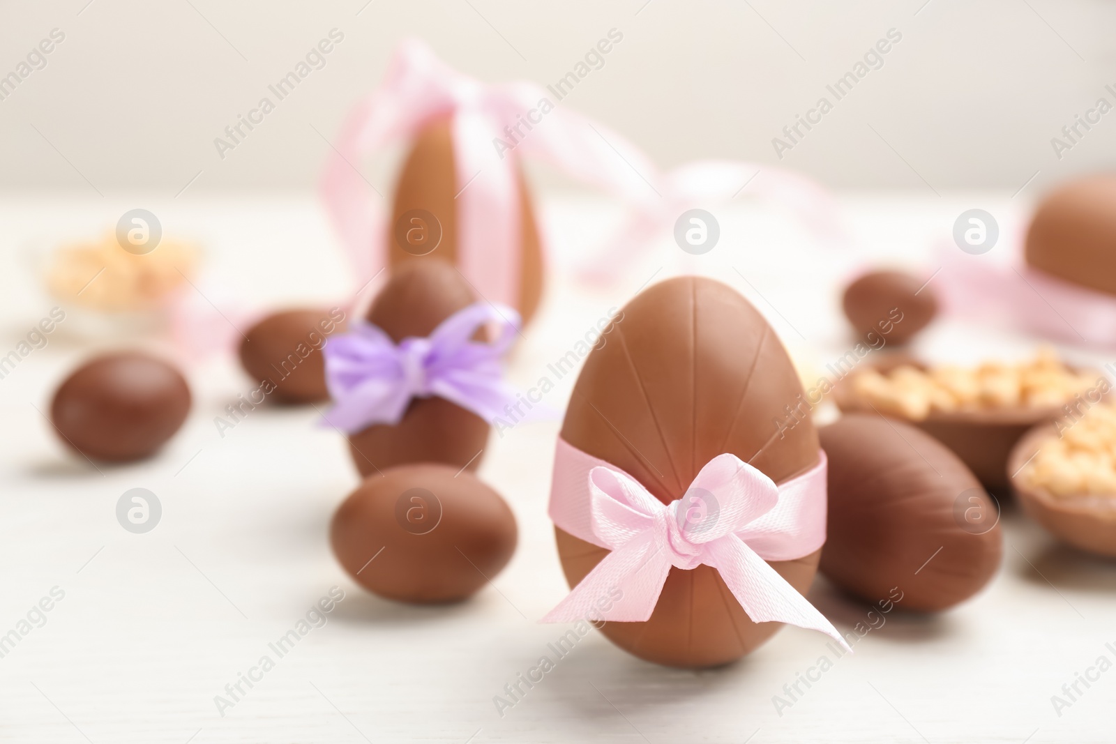 Photo of Sweet chocolate eggs on white wooden table. Space for text