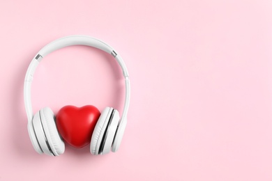 Photo of Modern headphones and red heart on pink background, flat lay with space for text. Listening love music songs