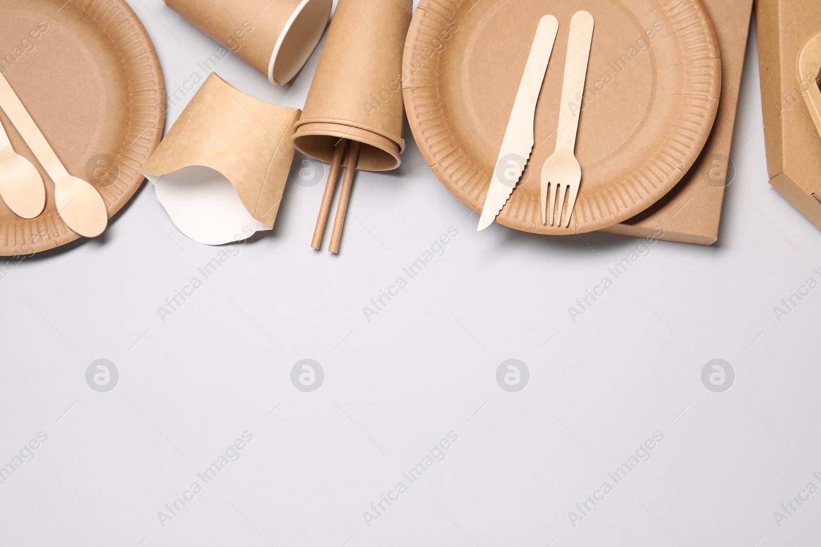 Photo of Eco friendly food packaging. Paper containers and tableware on light grey background, flat lay. Space for text