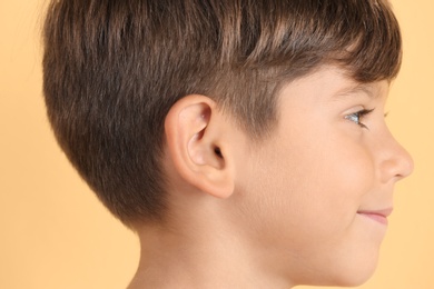 Cute little boy on color background, closeup. Hearing problem