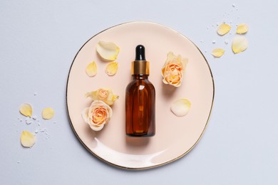 Bottle of cosmetic serum and beautiful flowers on light grey background, flat lay